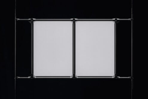 Industrial metal clamps suspending dual blank posters on black background