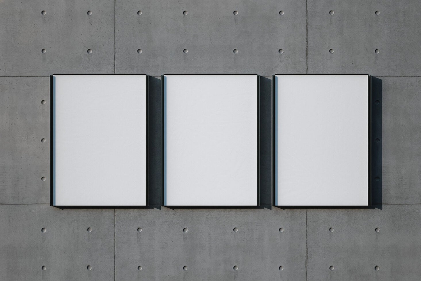 Three black-framed canvas mockups on concrete wall with rivet details