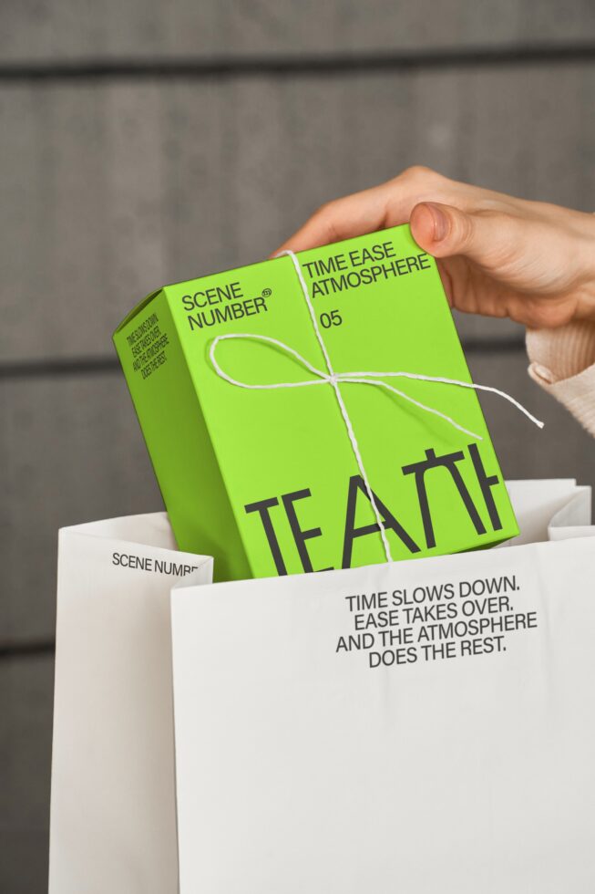 Hands pulling lime green tea box tied with white string from white paper packaging