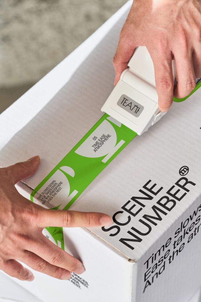 Hand pulling white label off lime green tea box mockup showing wraparound design