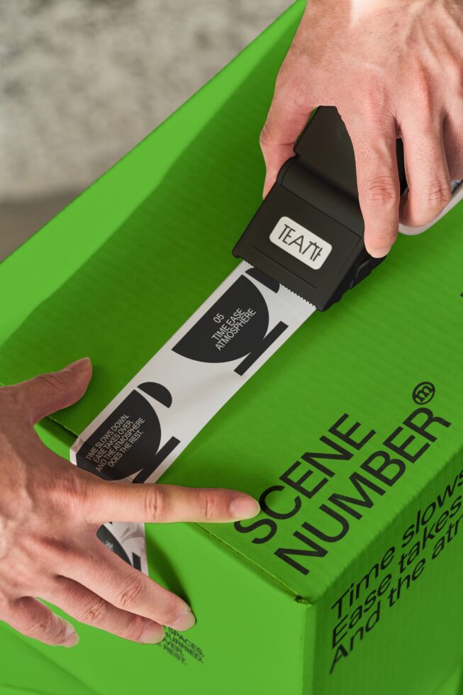 Hand peeling back black label on bright green tea box mockup closeup