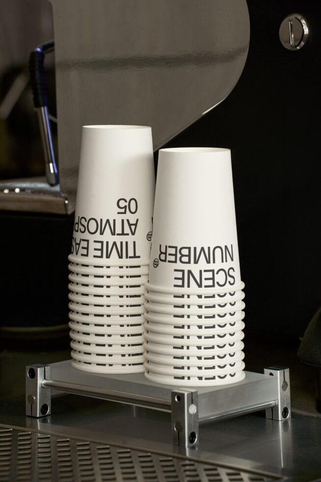 Stacked white paper cups with black text on metal stand in studio setup