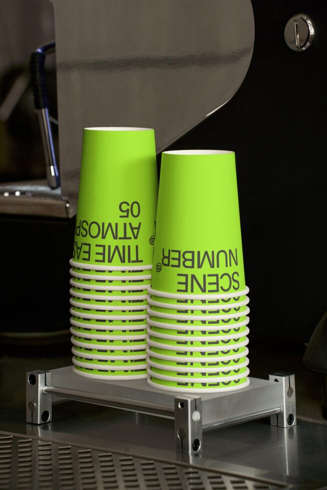Stacked neon green paper cups with black text in industrial studio setting