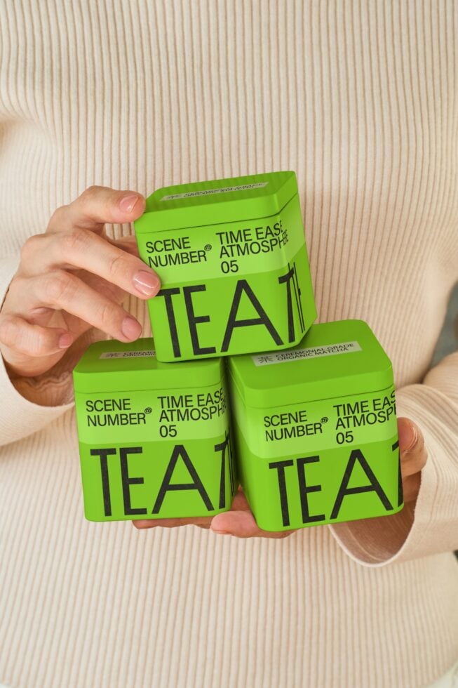 Three bright lime packaging boxes with Scene Number 05 Tea branding in hand