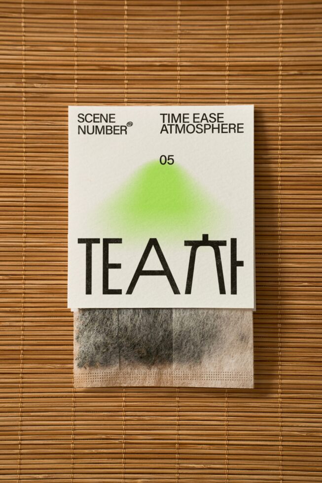 Minimalist tea packaging on wooden mat with bold TEATH typography green gradient