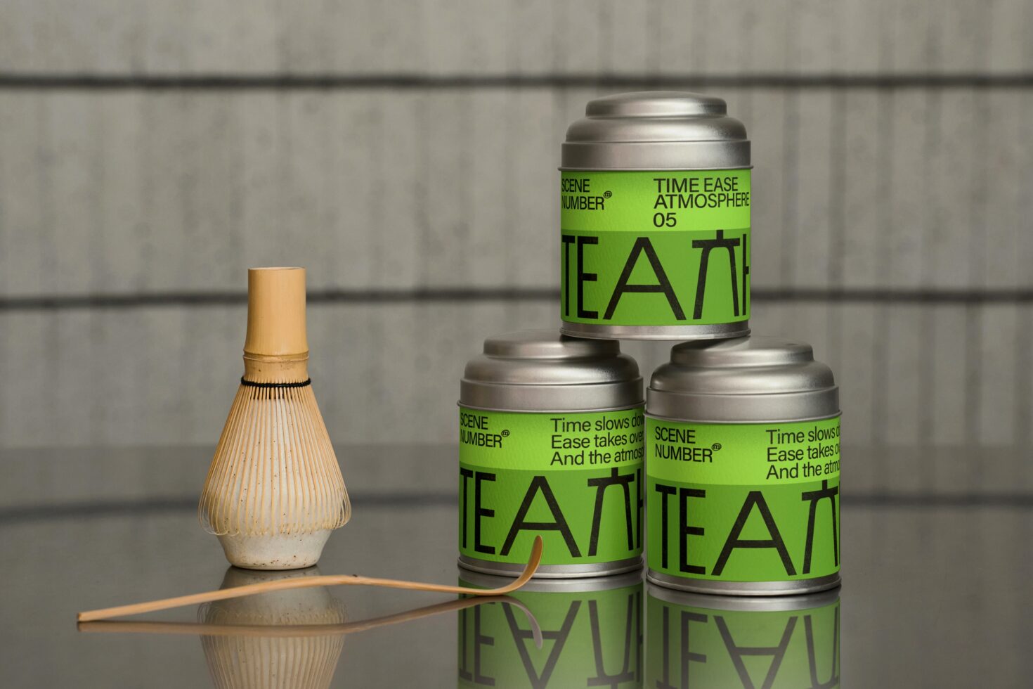 Three green tins stacked in pyramid with whisk, concrete background