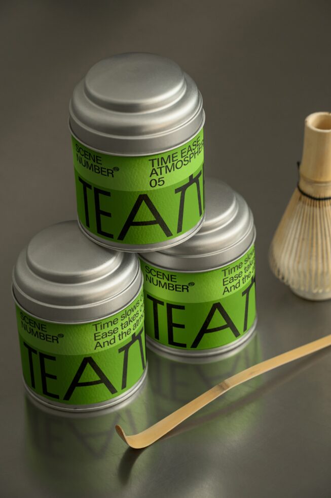 Three stacked green tea tins with silver lids, wooden whisk beside
