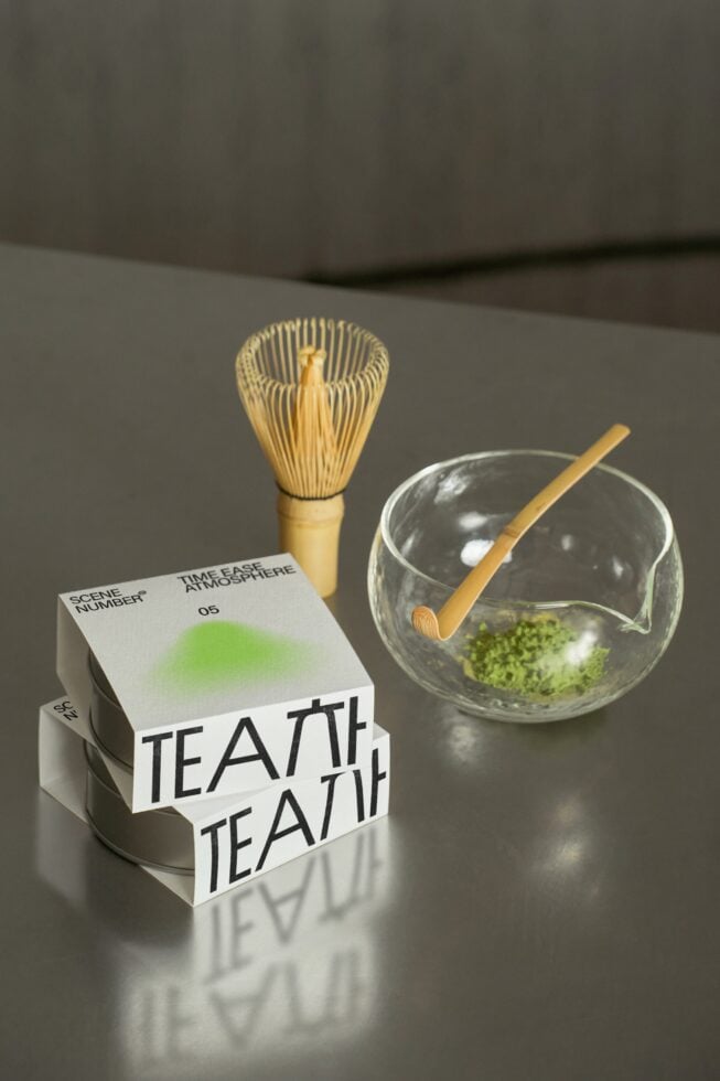 Matcha tea ceremony setup with bamboo whisk, glass bowl, wooden spoon, branded box