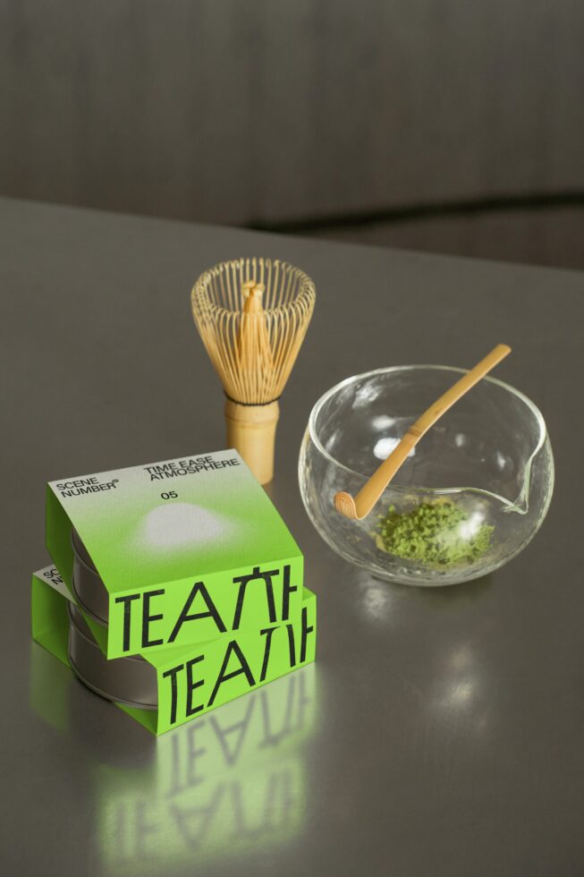 Green tea box stacked with wooden whisk, glass bowl, matcha setup
