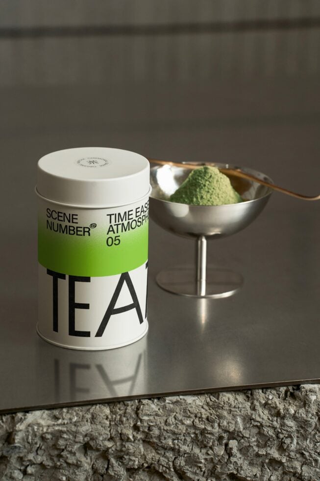 White cylindrical tea container with green band stripe, matcha bowl nearby