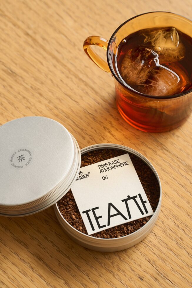 Overhead shot of loose tea container, glass with iced beverage on wood table