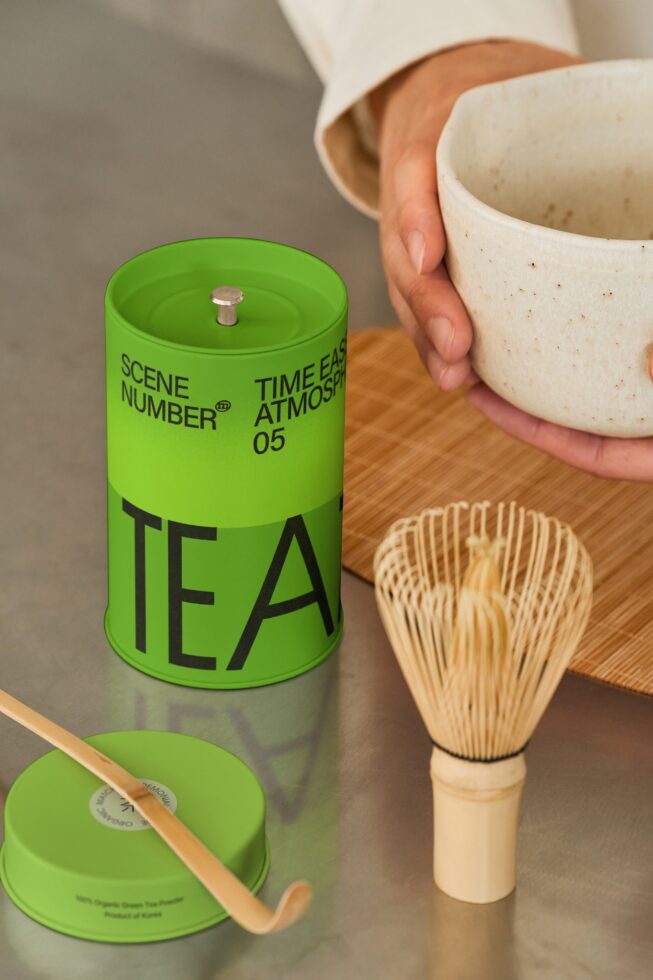 Bright green tea candle with bamboo whisk, ceramic bowl, wooden mat styling