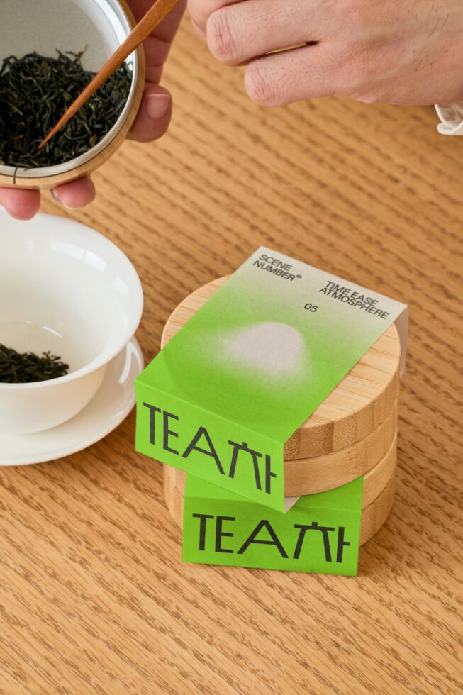 Neon green tea box packaging with loose leaf next to white cup