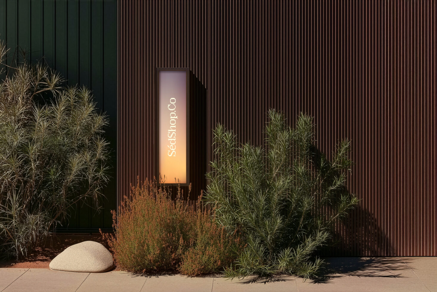 Tall vertical sign glowing with gradient light surrounded by desert plants