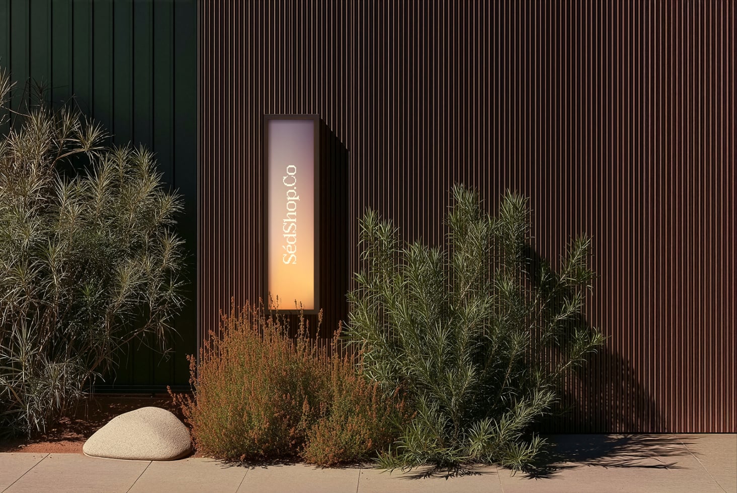 Tall vertical sign mockup nestled between ornamental grasses with warm gradient glow on corrugated metal wall