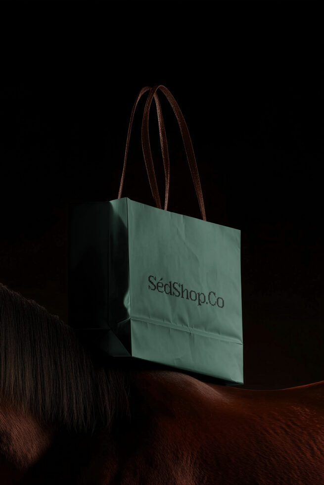 Sage green shopping bag with brown leather handles on dark background