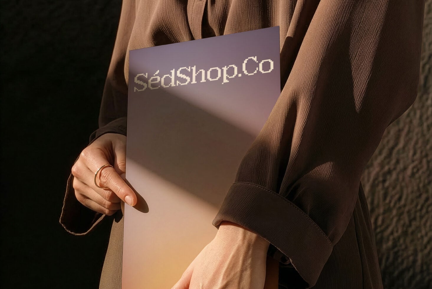 Hands displaying mauve gradient card with sunlight casting shadows
