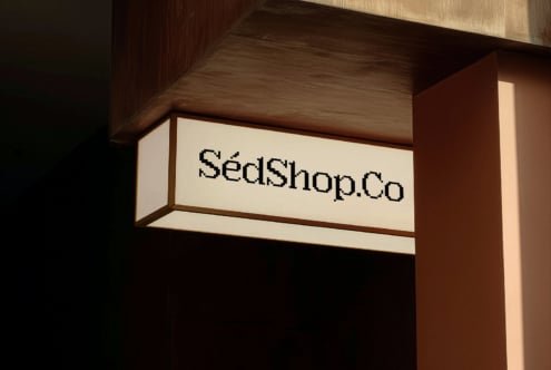 Illuminated storefront signage showing SedShop.Co in cream with wooden surround