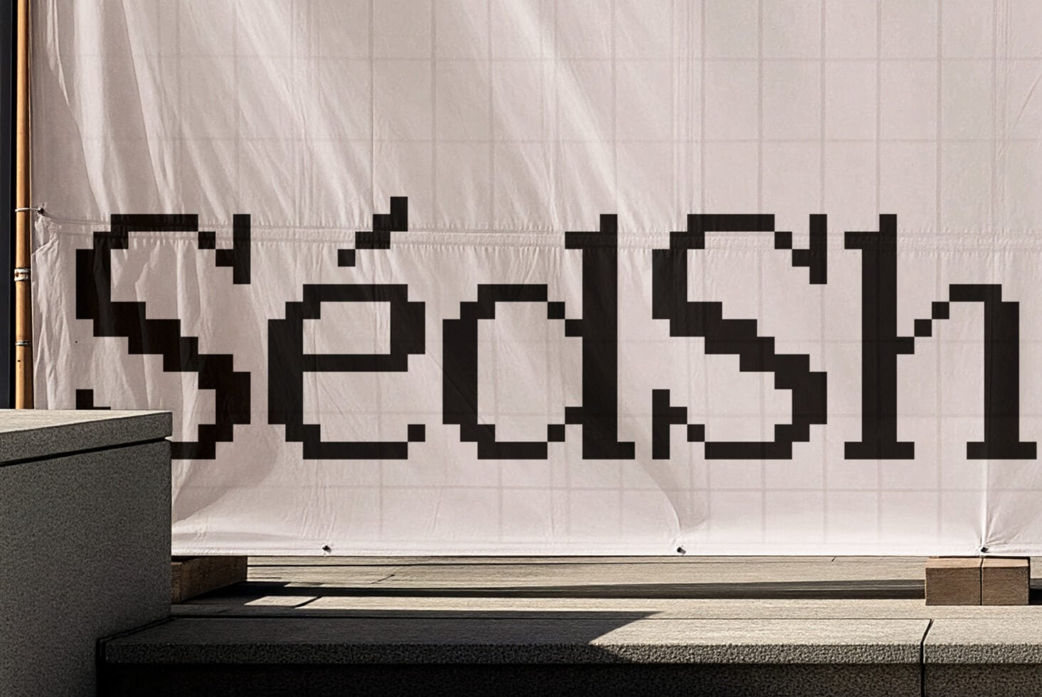 Pixelated black font text on beige fabric storefront banner with grid pattern