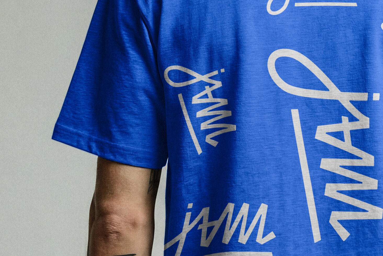 Blue shirt detail showing jWML wavy logo text in white on fabric