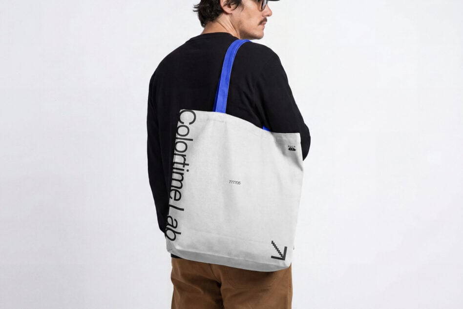 Person wearing cream colored tote bag with blue strap over black shirt