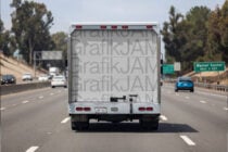 Truck rear on highway showing light gray repeated text wrap design