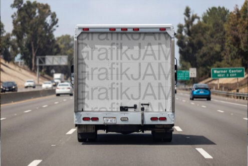 Truck rear on highway showing light gray repeated text wrap design