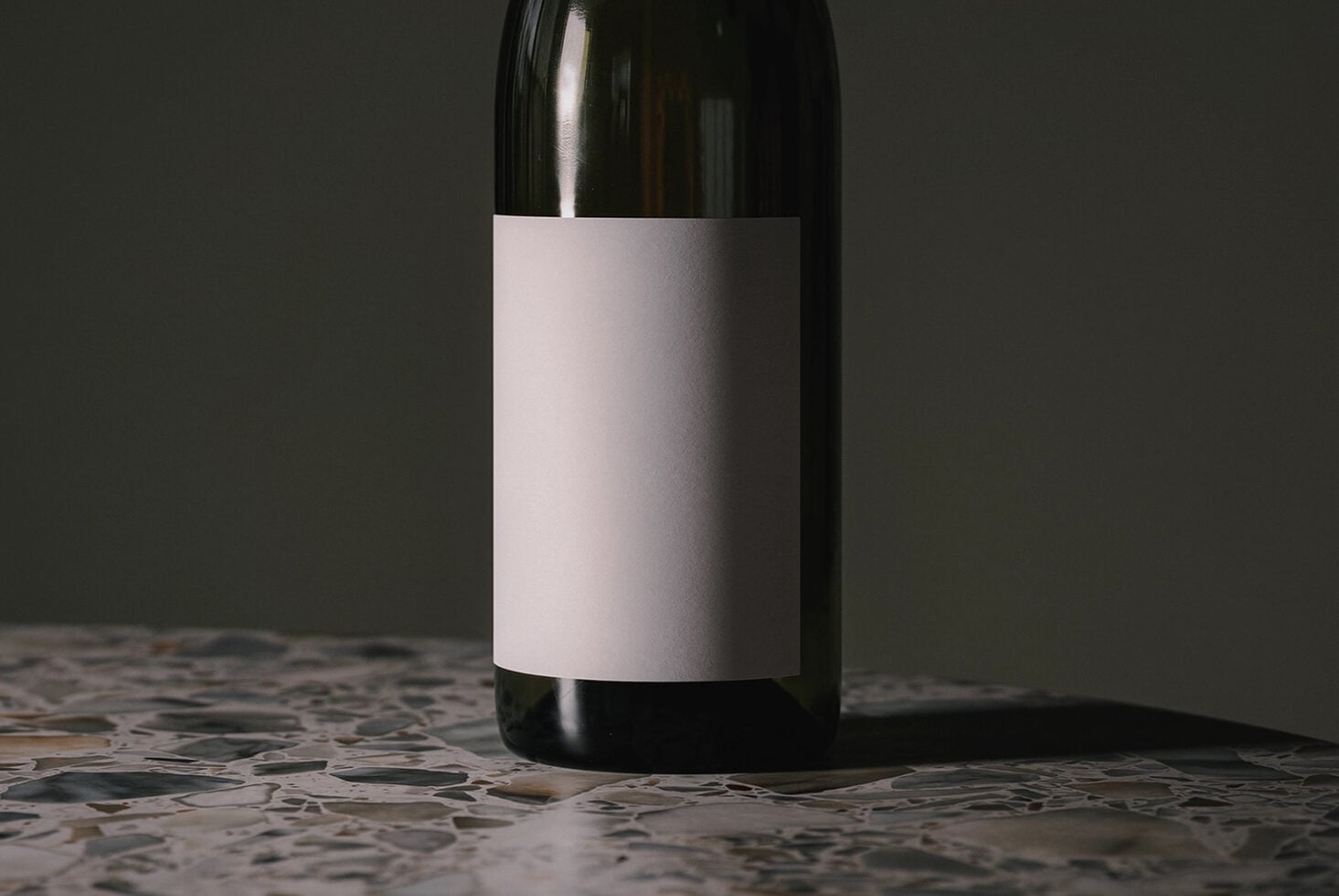Wine bottle with blank white label positioned on speckled stone surface