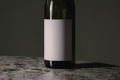 Wine bottle with blank white label positioned on speckled stone surface