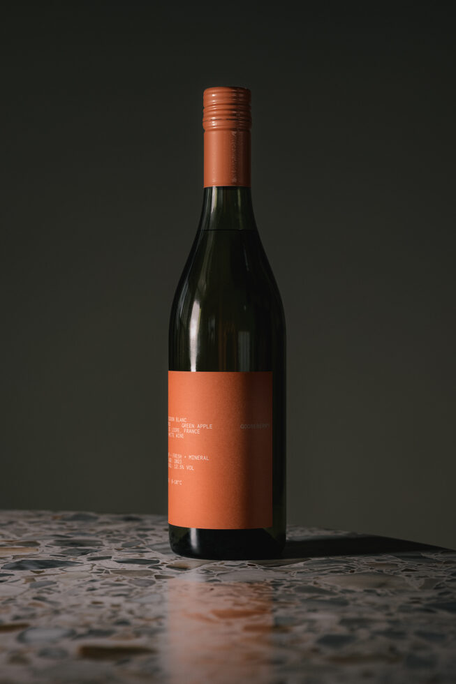 Full wine bottle mockup with coral label on textured concrete background
