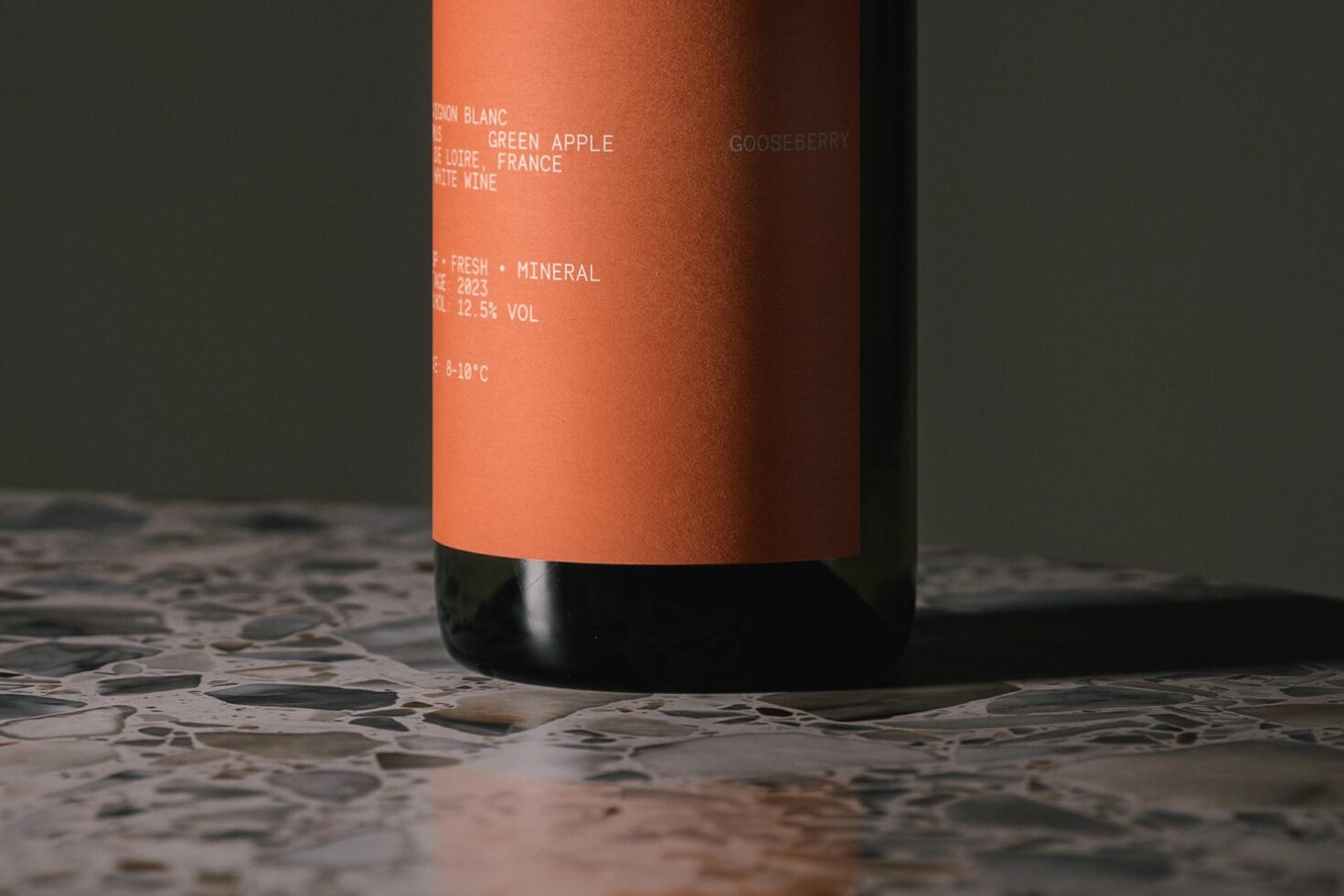 Wine bottle detail shot with burnt orange label showing tasting notes on terrazzo surface
