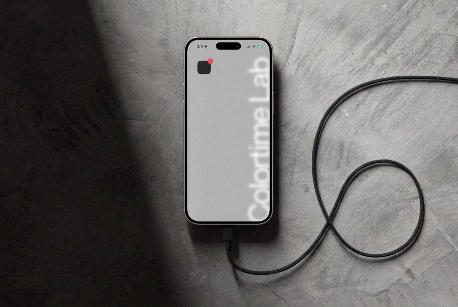 White iPhone with minimalist wallpaper, black charging cable looped on textured background