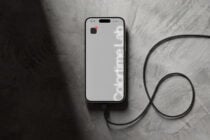 White iPhone with minimalist wallpaper, black charging cable looped on textured background