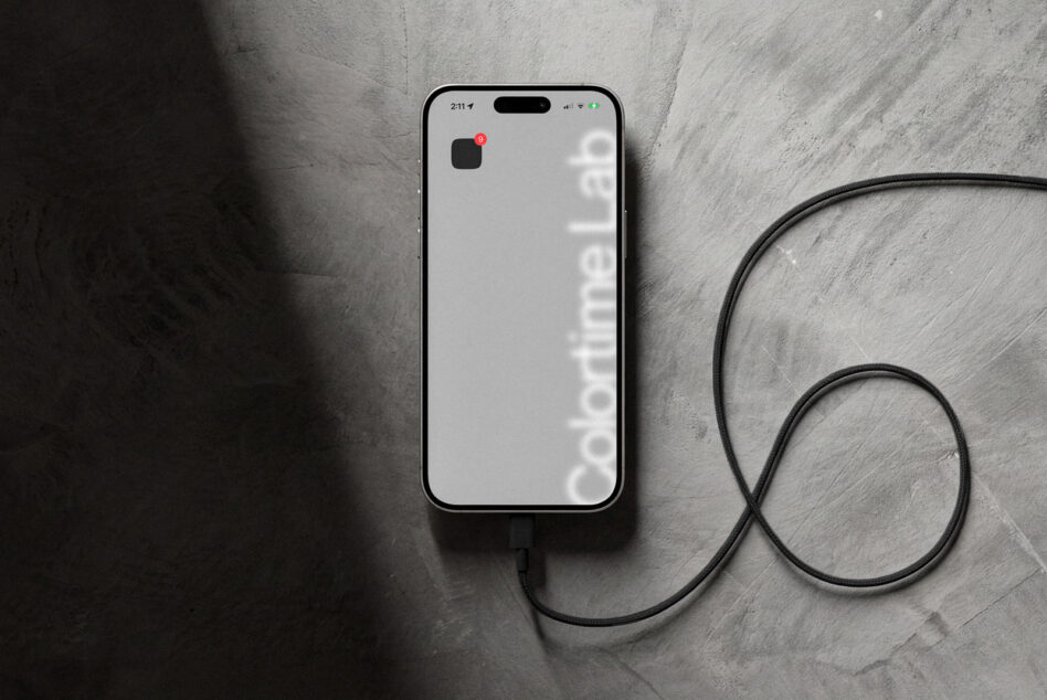 White iPhone with minimalist wallpaper, black charging cable looped on textured background