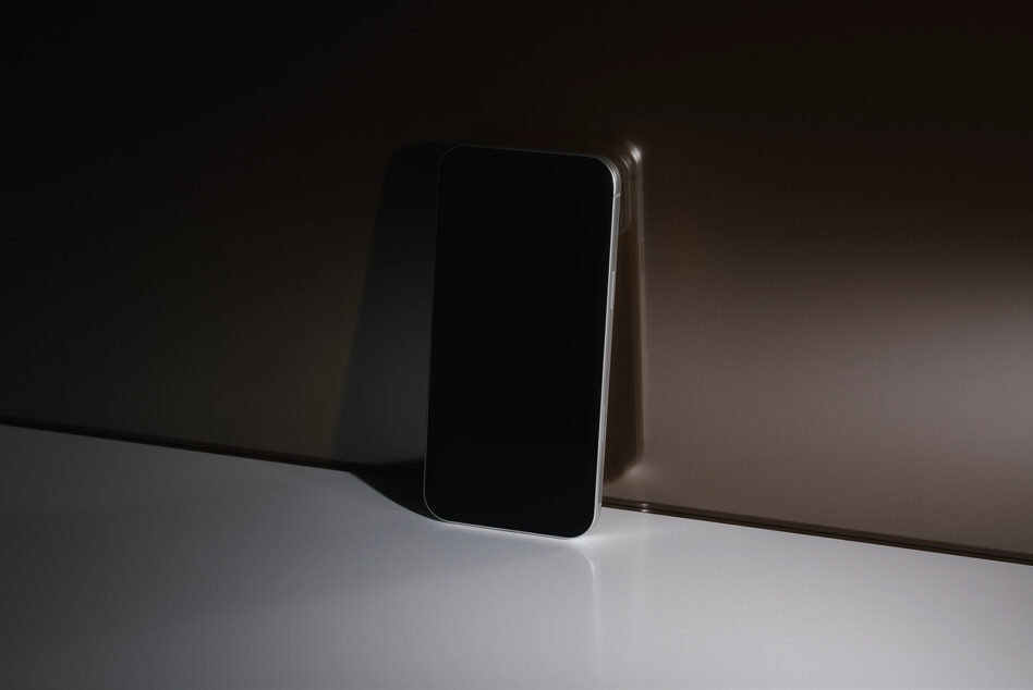 Smartphone mockup with blank black screen, chrome edge, minimal setup shot
