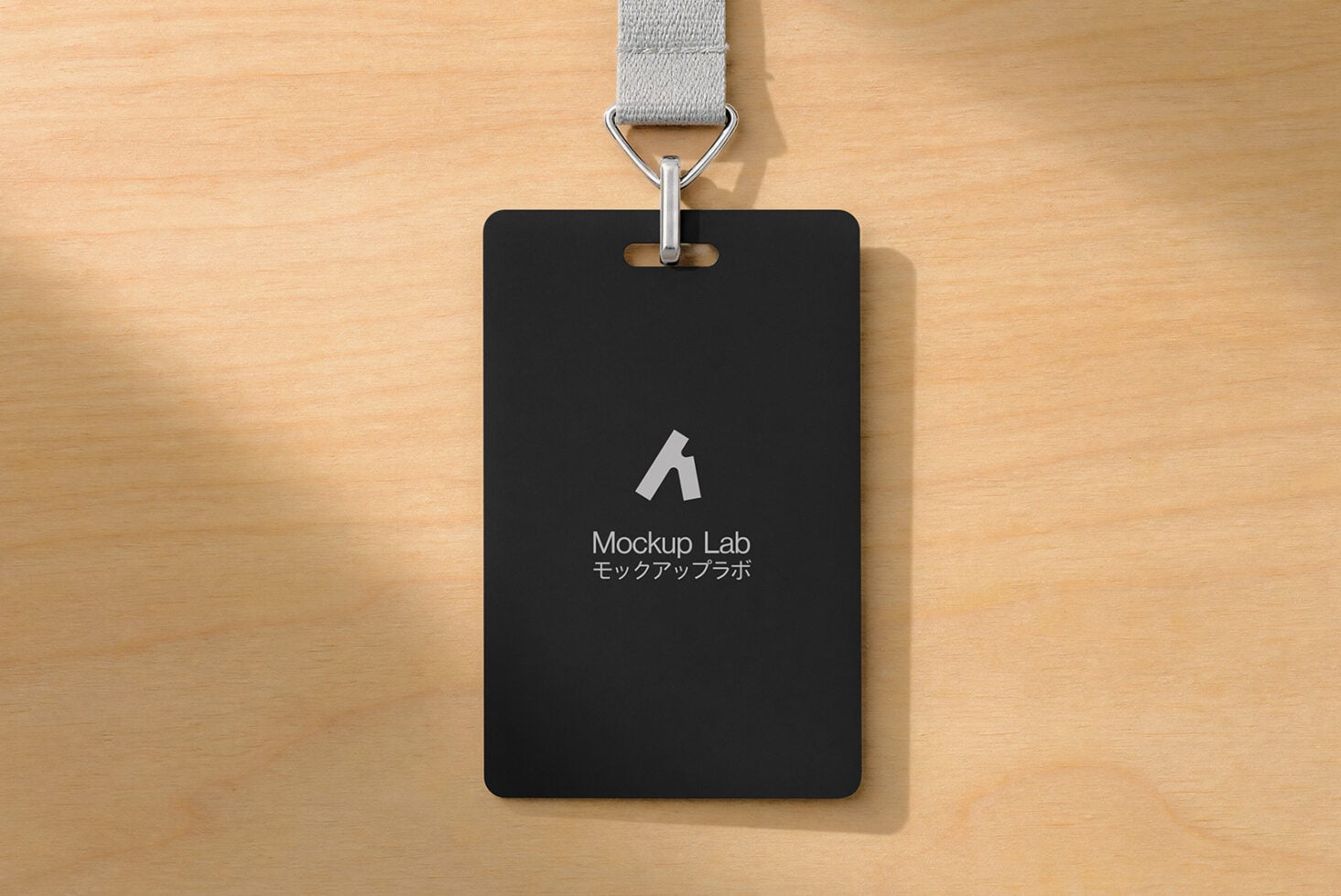 Black ID badge mockup with gray fabric lanyard on wooden surface