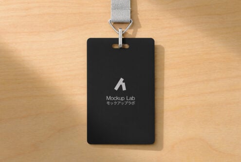 Black ID badge mockup with gray fabric lanyard on wooden surface