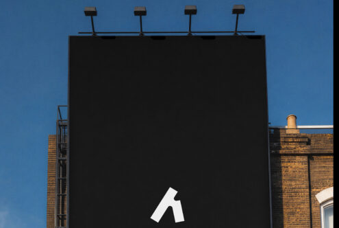 Blank billboard with four lights mounted on top against clear blue sky