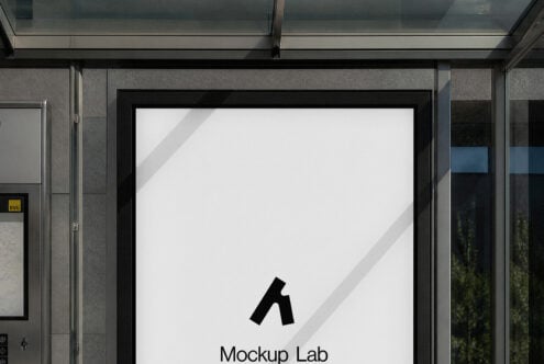 Storefront window mockup with black frame showing blank white poster, sunlight casting diagonal shadows