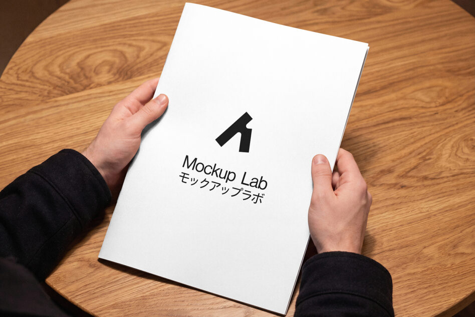 White book cover held in hands showing Mockup Lab logo with Japanese text