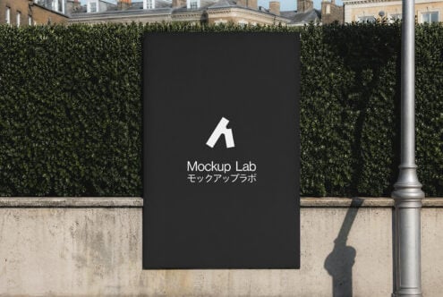 Black billboard mockup mounted on hedged urban wall with London townhouses behind