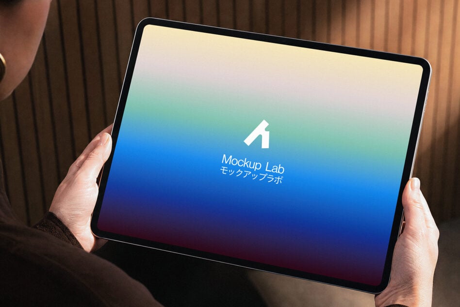 Hands holding tablet with gradient screen showing Mockup Lab logo