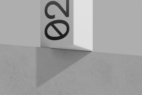 Logo mockup on folded white paper with concrete floor, bold black letterforms casting shadows