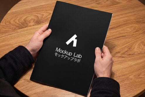Black book cover held in hands displaying Mockup Lab branding with Japanese characters