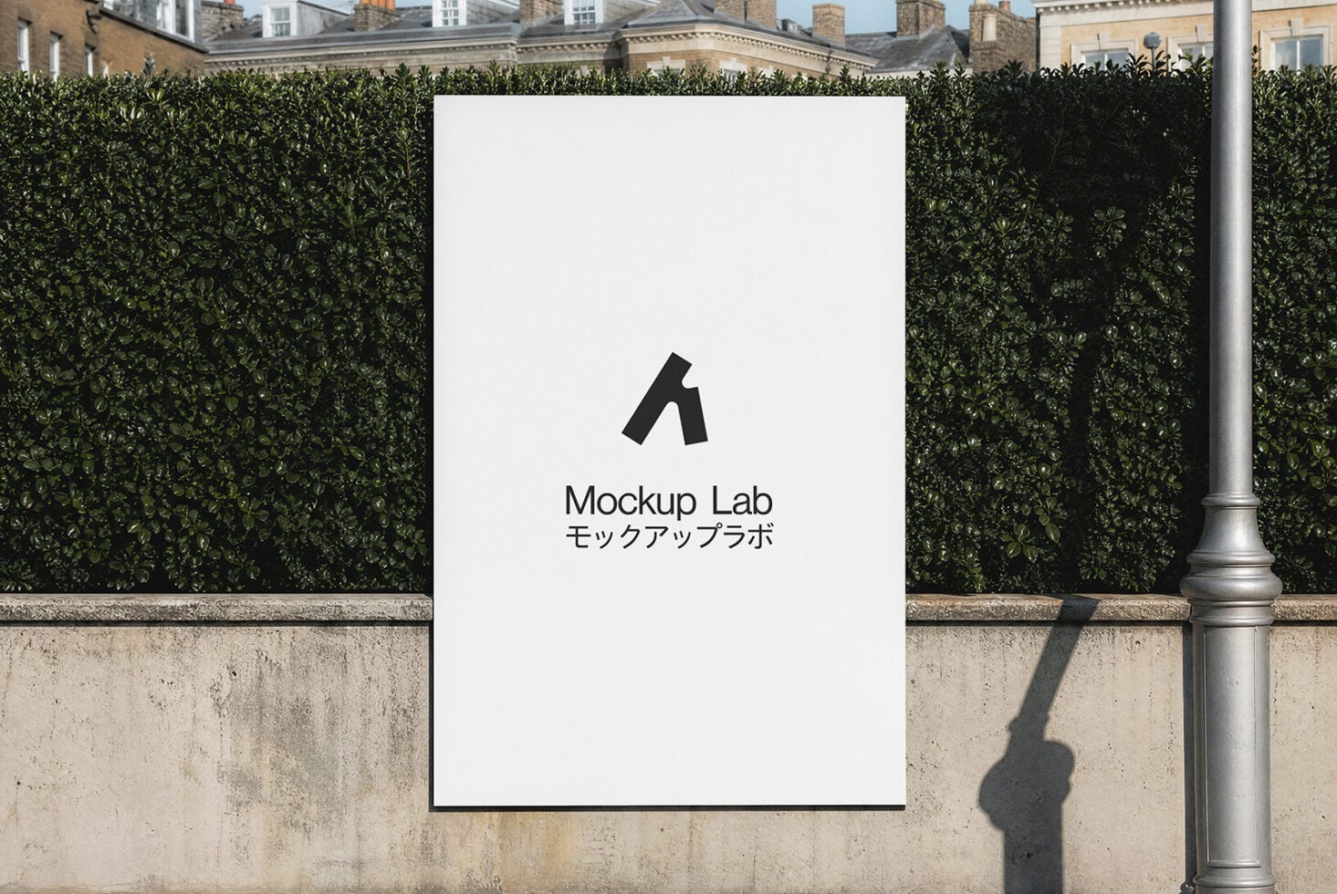 White poster mounted on concrete wall with hedge backdrop, displaying logo with Japanese text