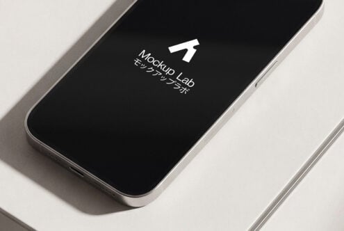 Silver smartphone angled flat lay with black screen displaying white Mockup Lab icon