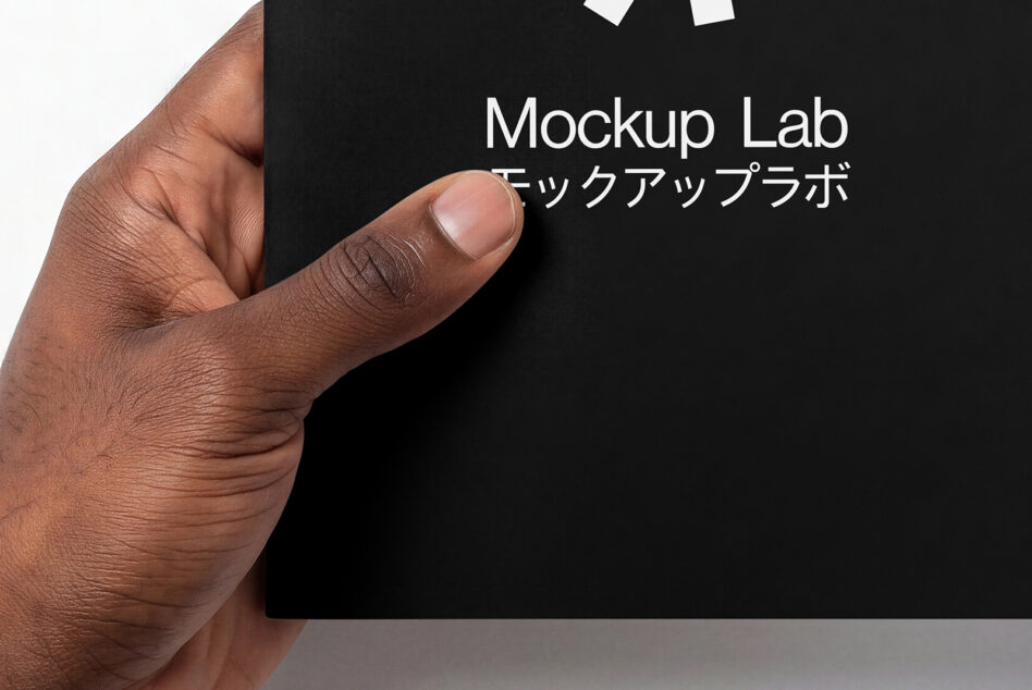 Hand holding black business card with white Mockup Lab logo centered