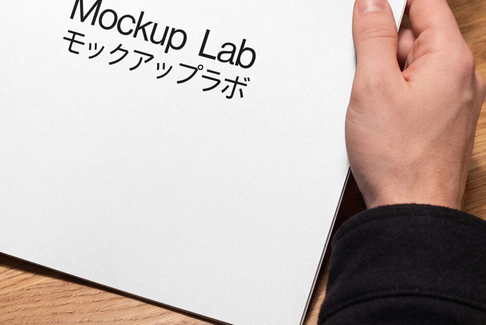 Overhead shot of white paper held in hand showing black Mockup Lab text overlay