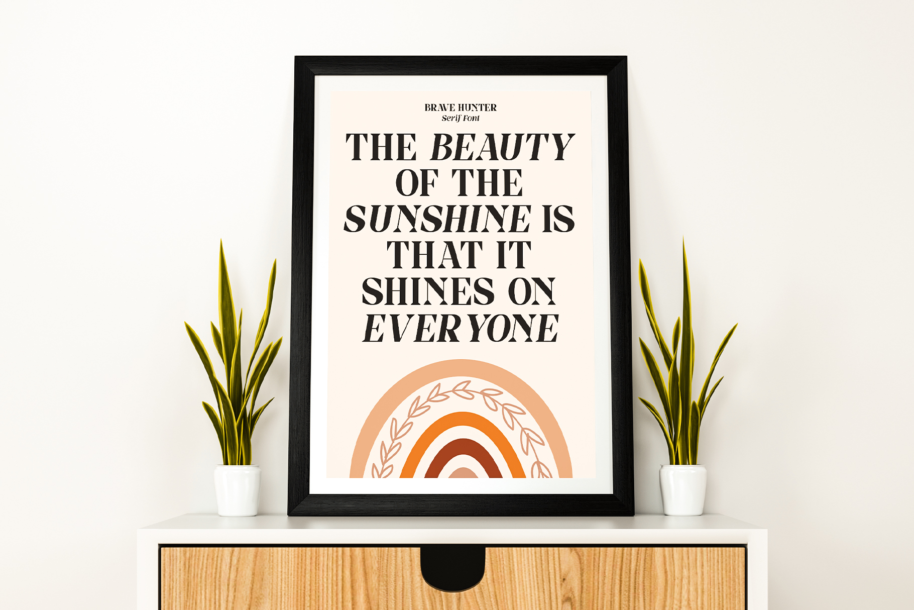 Framed motivational typography poster with rainbow graphic on wooden shelf with plants