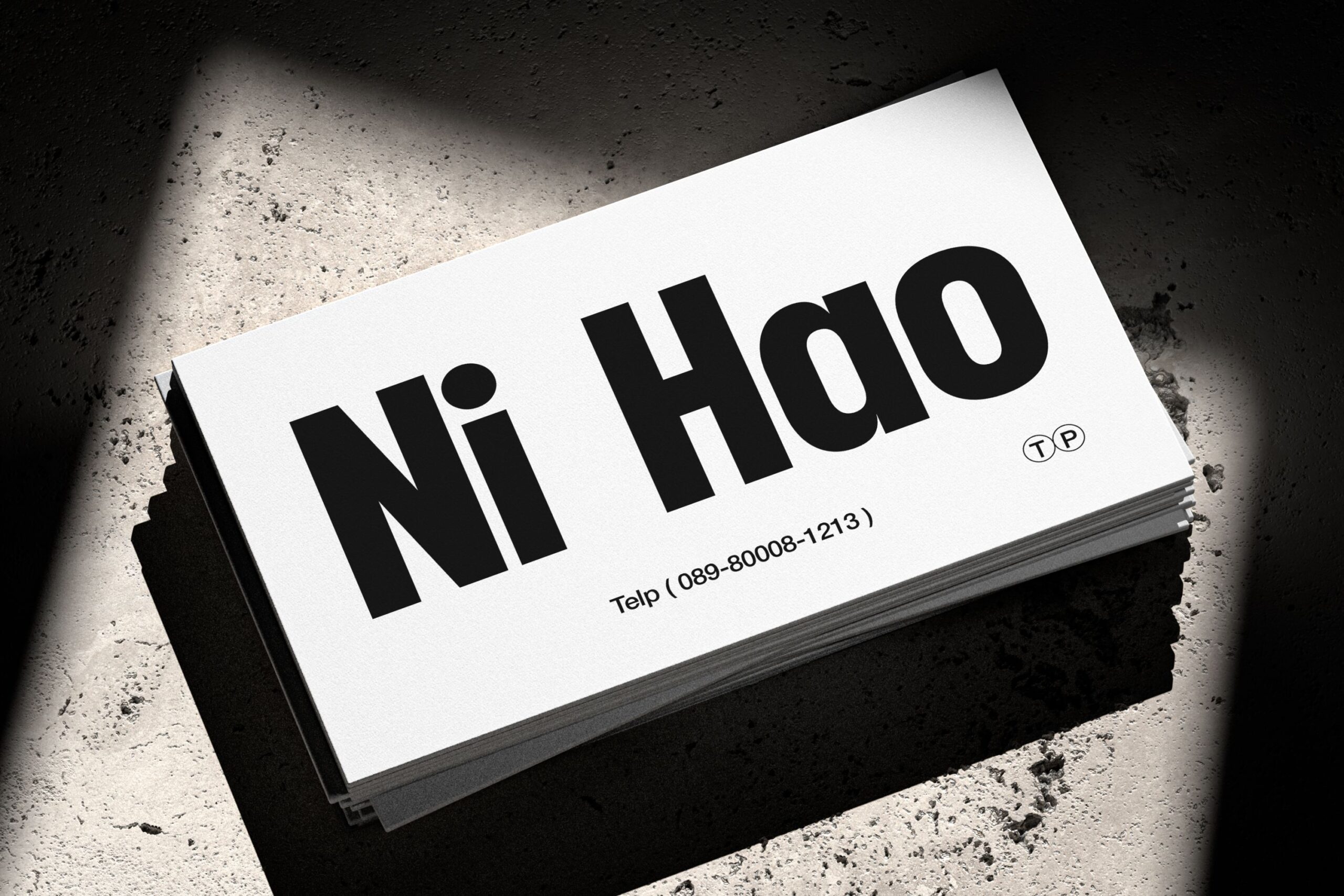 Stack of business cards showing Ni Hao branding in concrete setting